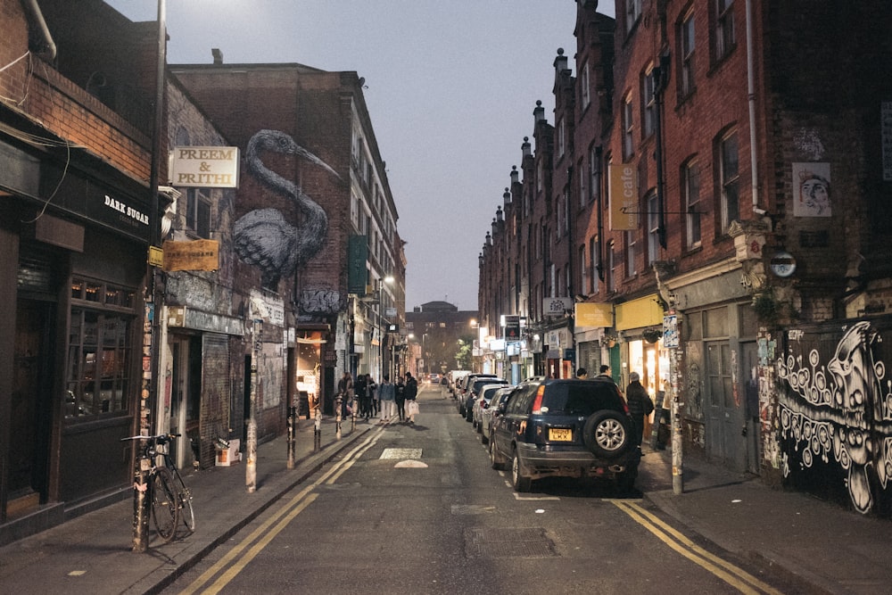 vehicles park on road between buildings