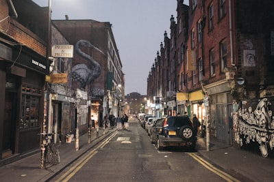 vehicles park on road between buildings