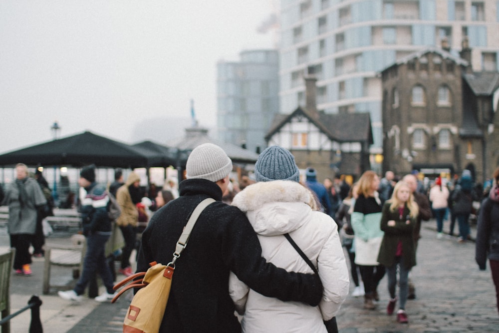 couple wearing jacket and knit caps walking on road