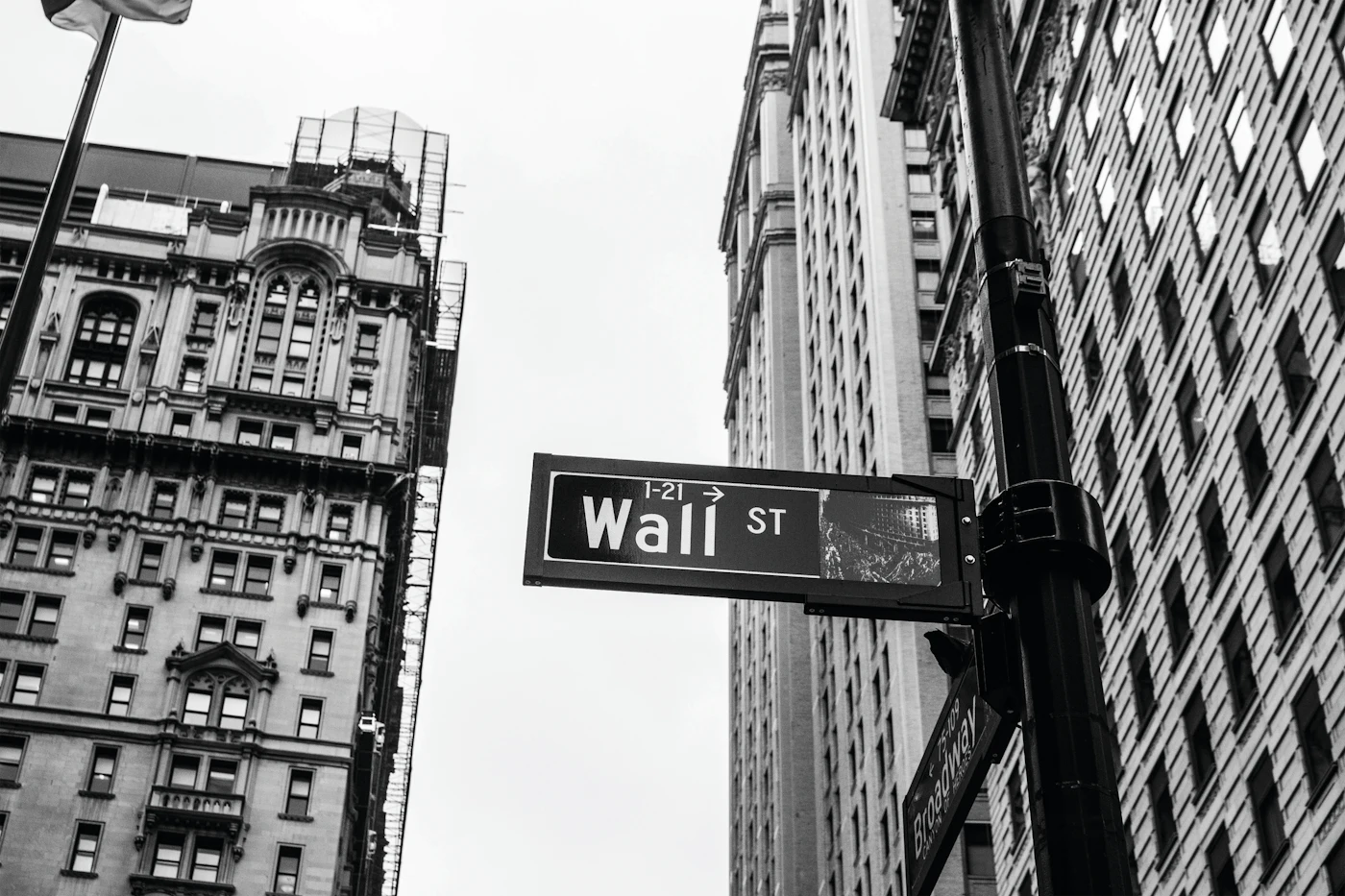 Black-and-white photo of a Wall Street street sign on a building corner in New York