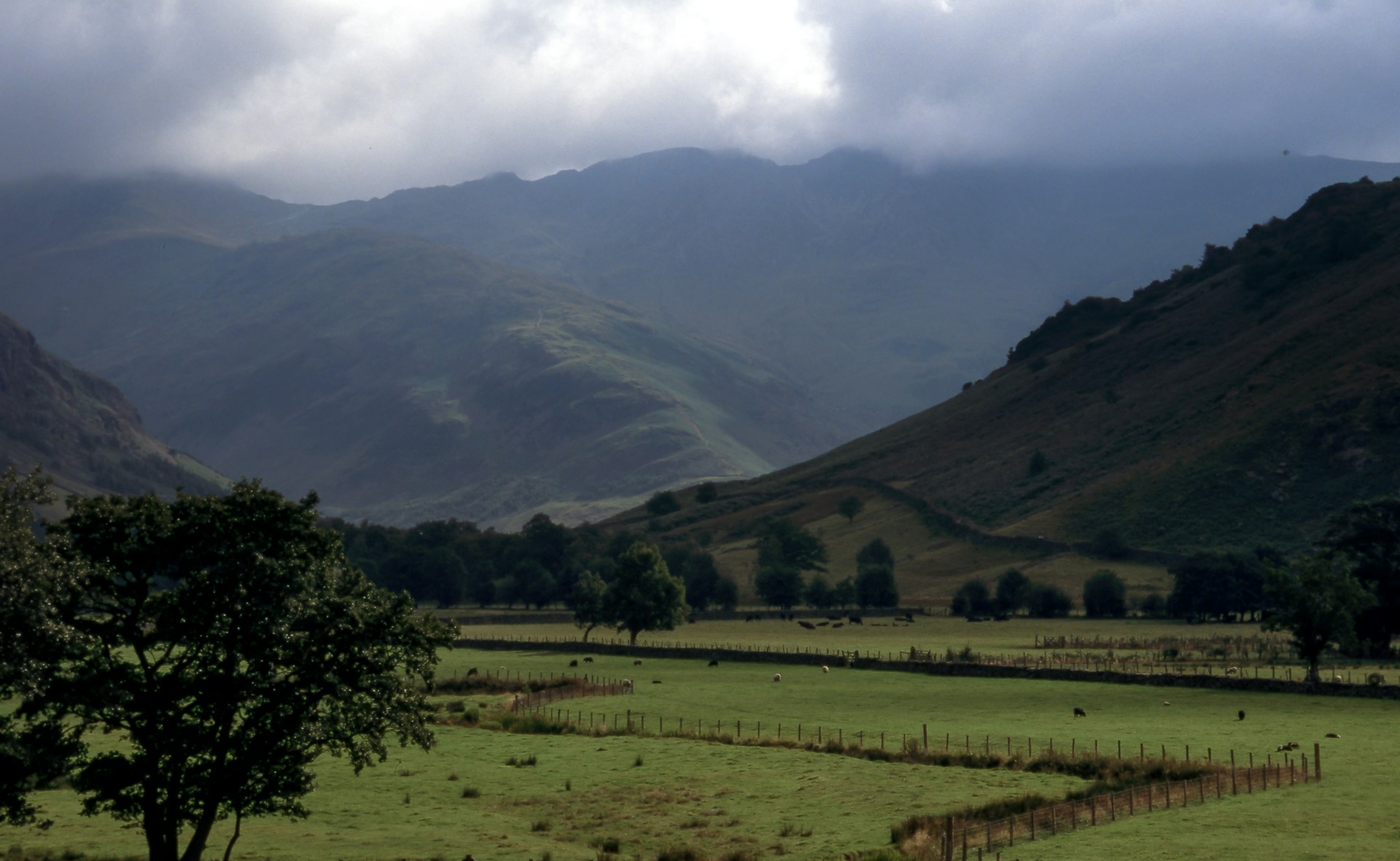 cloudy sky over mountains and grass field