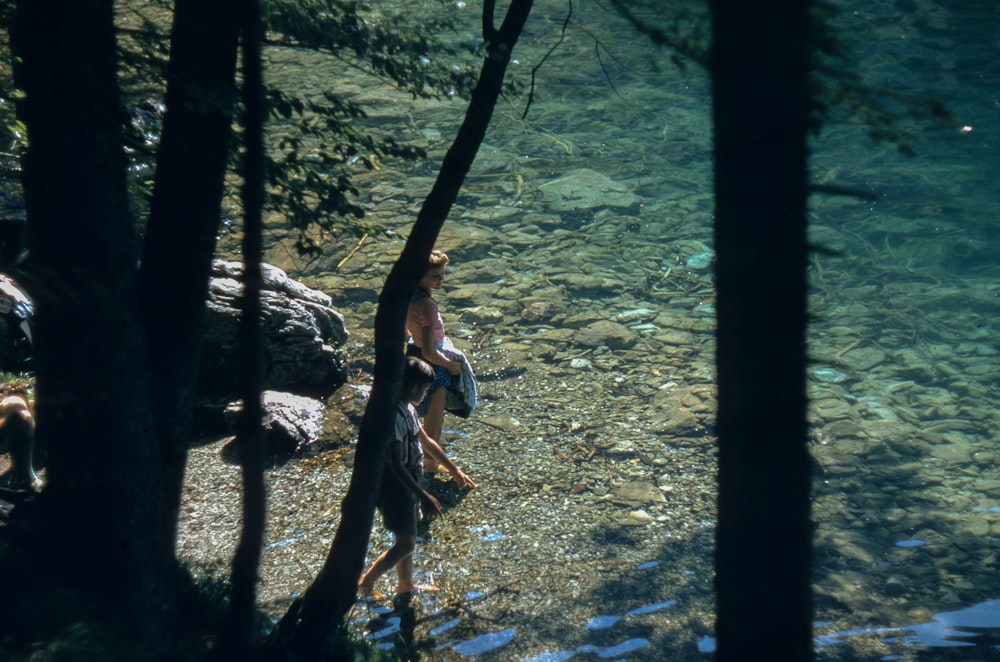 woman and boy standing near body of water