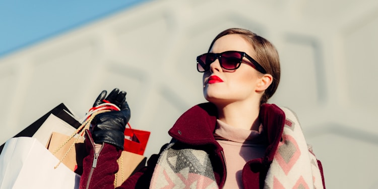 shallow focus photography of woman holding shopping bags during day