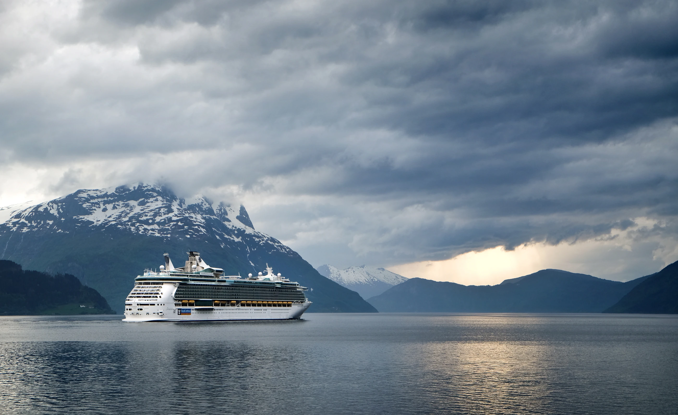 Ship beneath a mountain range at dusk