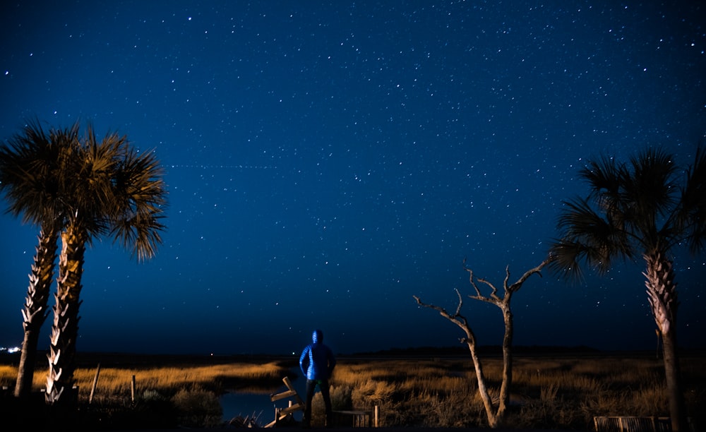 photo of person standing and looking clouds with stars