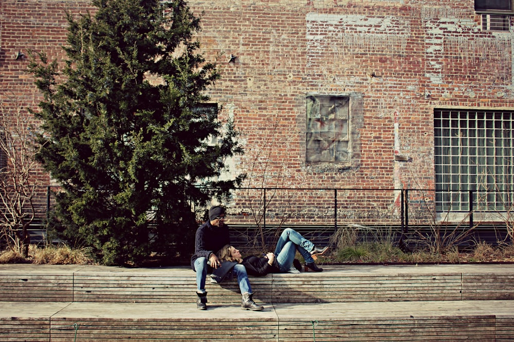 photo of woman laying on man's lap near green leafed tree