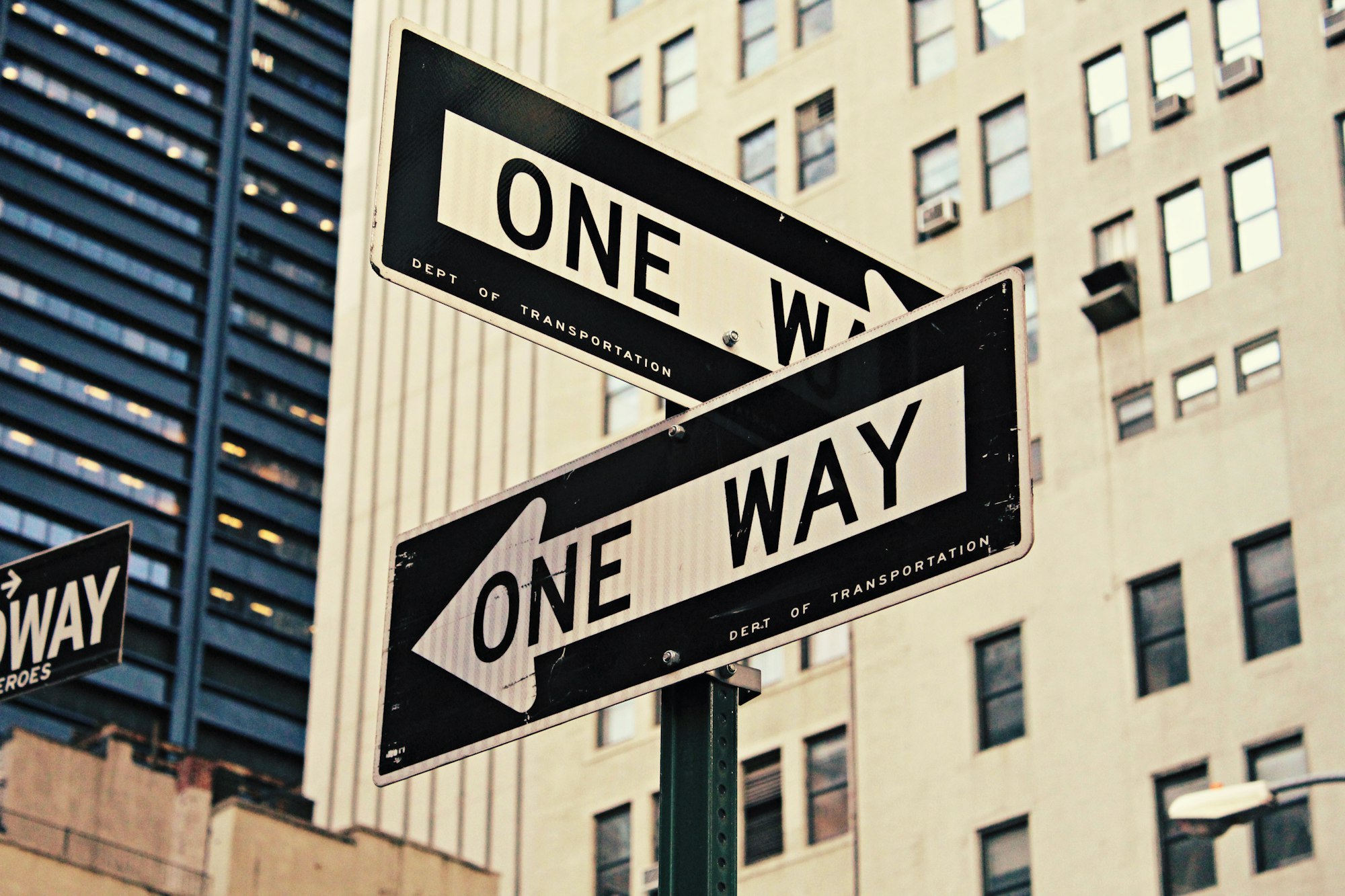 Duas placas se cruzam e sinalizam "one way" ou "mão única"