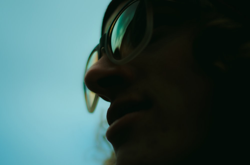 close up photo of person wearing glasses with teal background