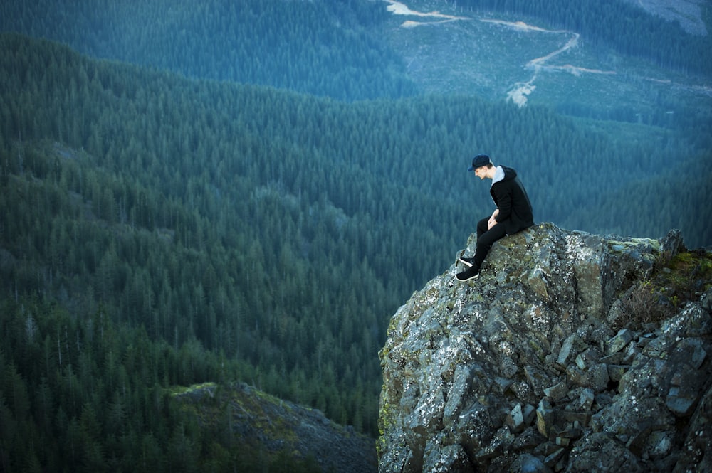 Photographie de vue aérienne sur l’homme assis sur la falaise