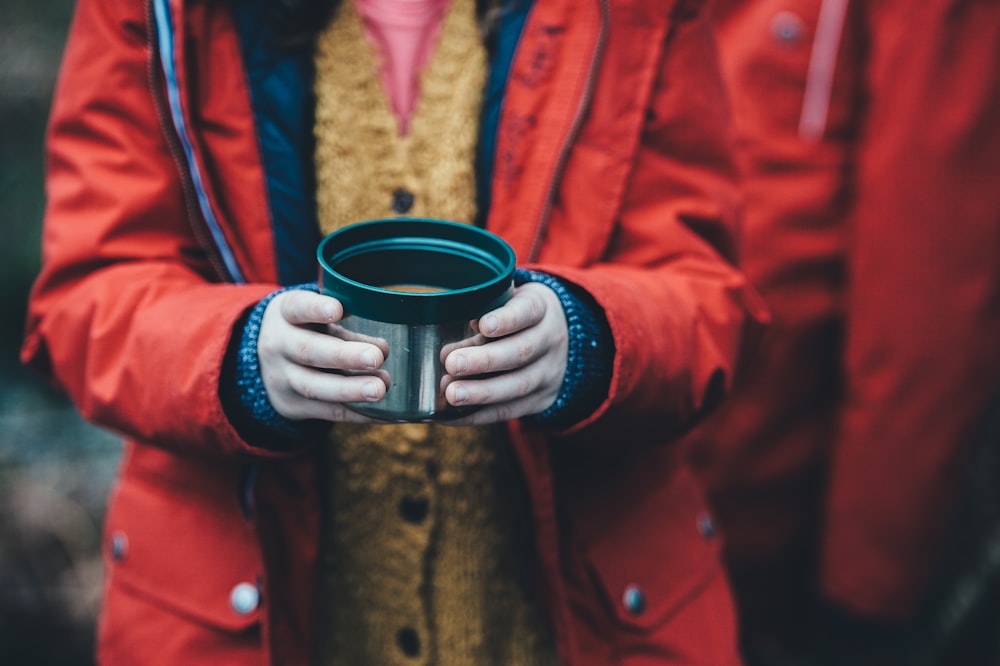 shallow focus photography of person holding green plastic container