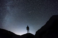 silhouette of man standing on hill during starry night