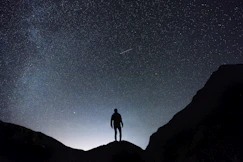 silhouette of man standing on hill during starry night