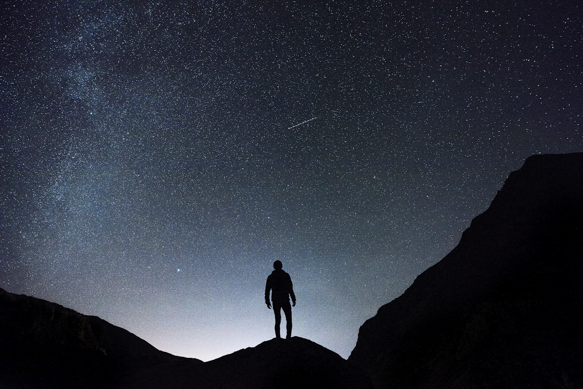 A lone figure beneath a luminous galaxy, the awakening