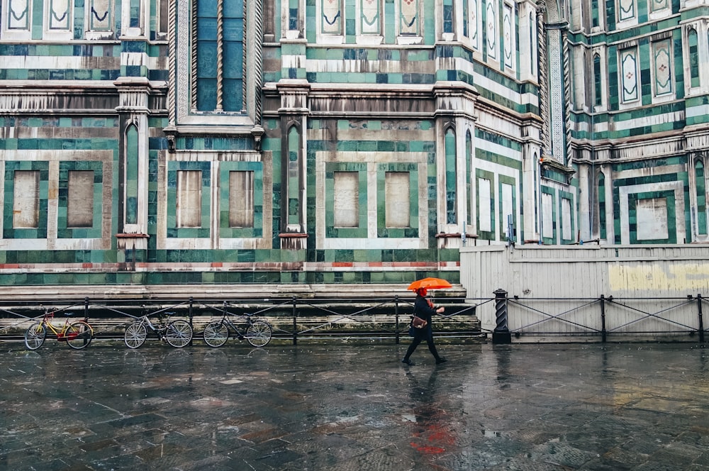 person holding umbrella walking on road