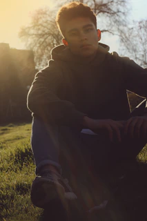Relaxed man meditating in a peaceful park with soft sunlight filtering through trees.