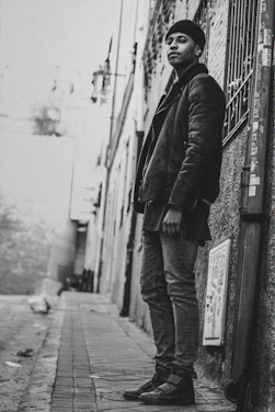 Black and white photo of a city alley with a person wearing a Junkwear hoodie, embodying street culture.