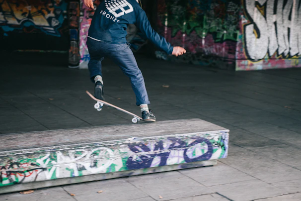 A young street skater crouched low, preparing to launch into a trick on a gritty urban ledge.