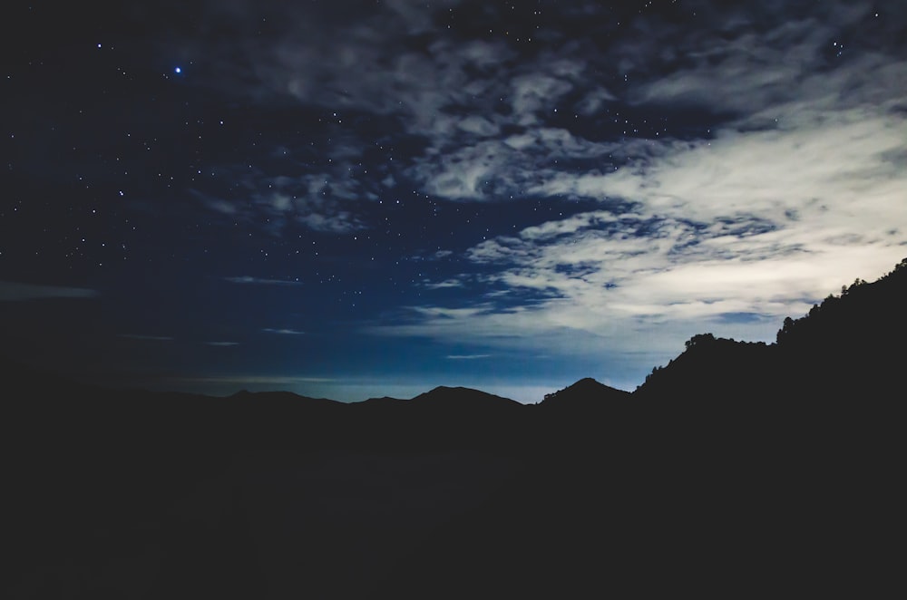 silhouette of mountain under white clouds