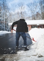 A friendly worker clearing snow from a driveway early in the morning.