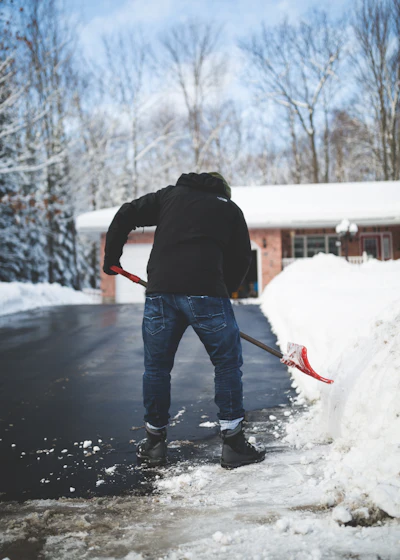 Worker shoveling snow from a residential driveway