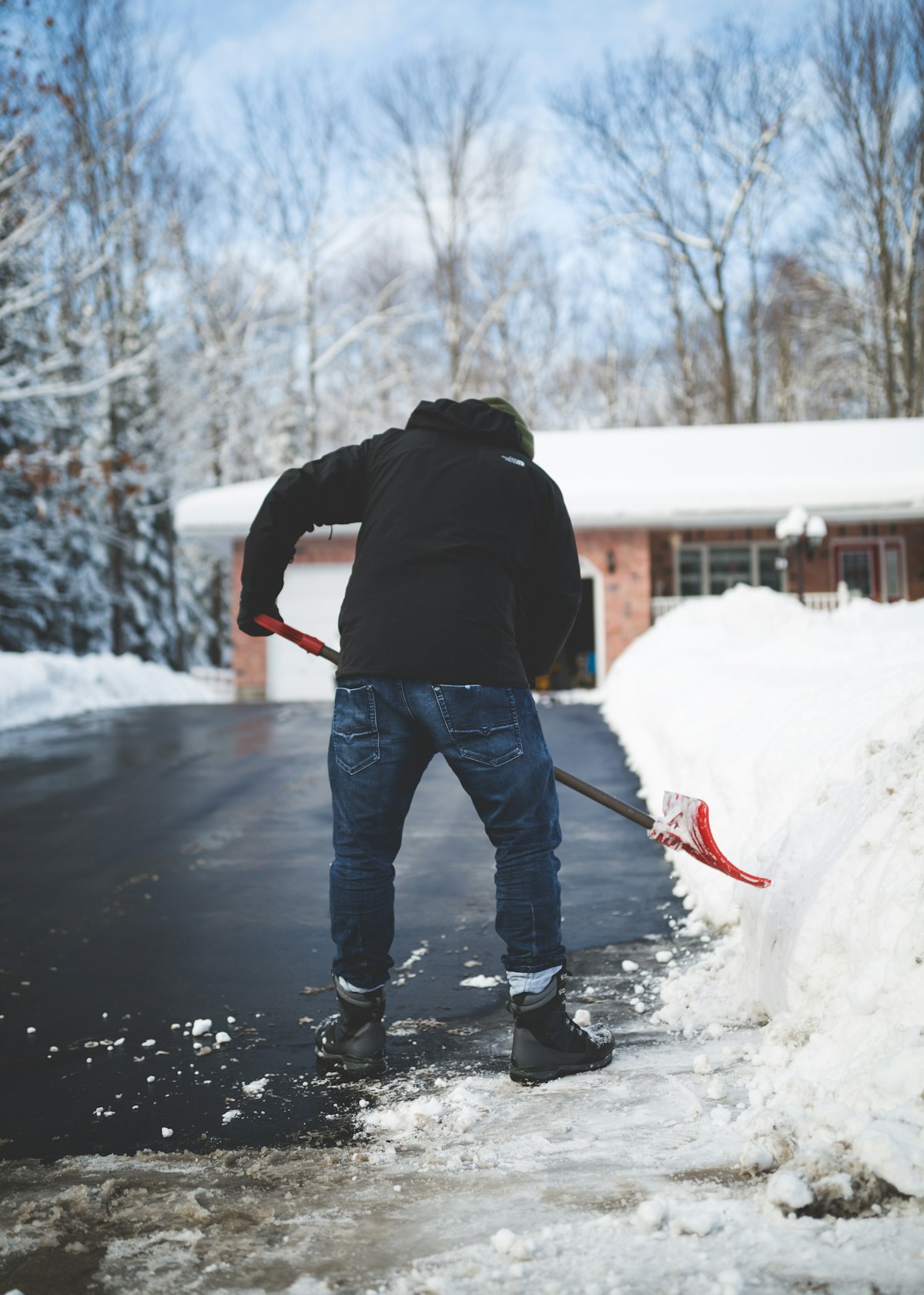 Person shoveling snow from a residential driveway in winter