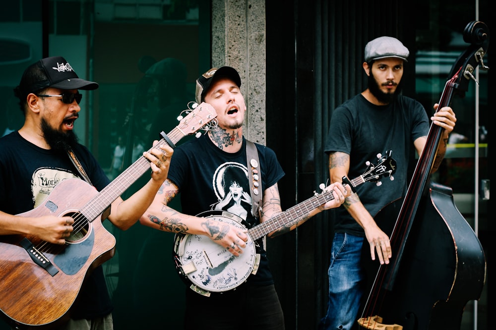 three men playing stringed instruments during daytime