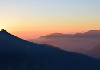 A warm, inviting photo of a traveler gazing at a golden sunset over a mountain range, embodying the spirit of adventure.
