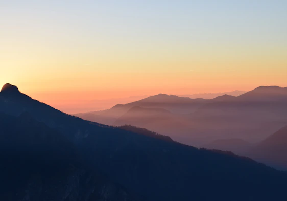 A warm, inviting photo of a traveler gazing at a golden sunset over a mountain range, embodying the spirit of adventure.