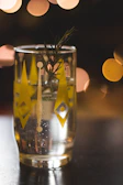 Close-up of a sparkling botanical beverage glass with dew drops glistening under soft light.