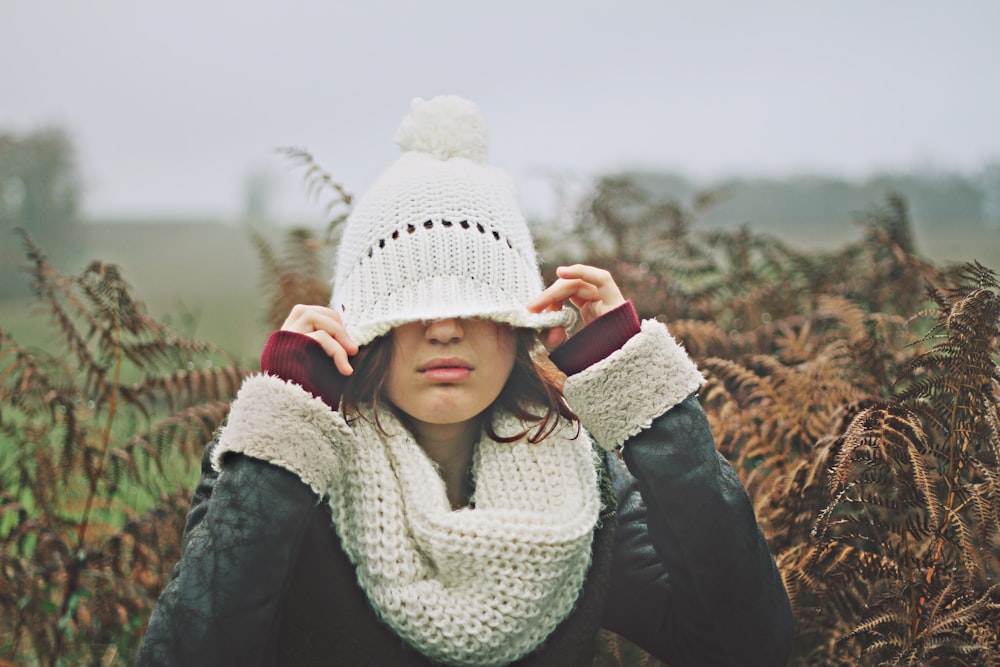 woman in white black sweater holding white knit cap