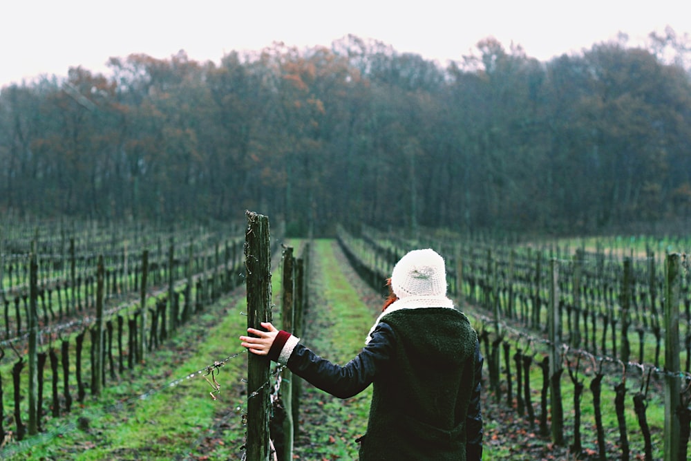 woman in black coat standing at vineyard