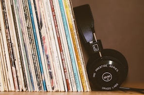 Close-up of vinyl records and headphones resting on a wooden table.