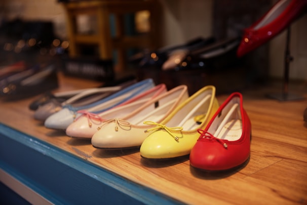 Flat shoes in neutral tones displayed on a soft beige fabric background.