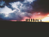 silhouette of nine persons standing on the hill