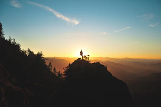 silhouette of man standing on mountain peak