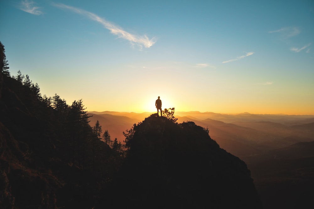 silhouette of man standing on mountain peak