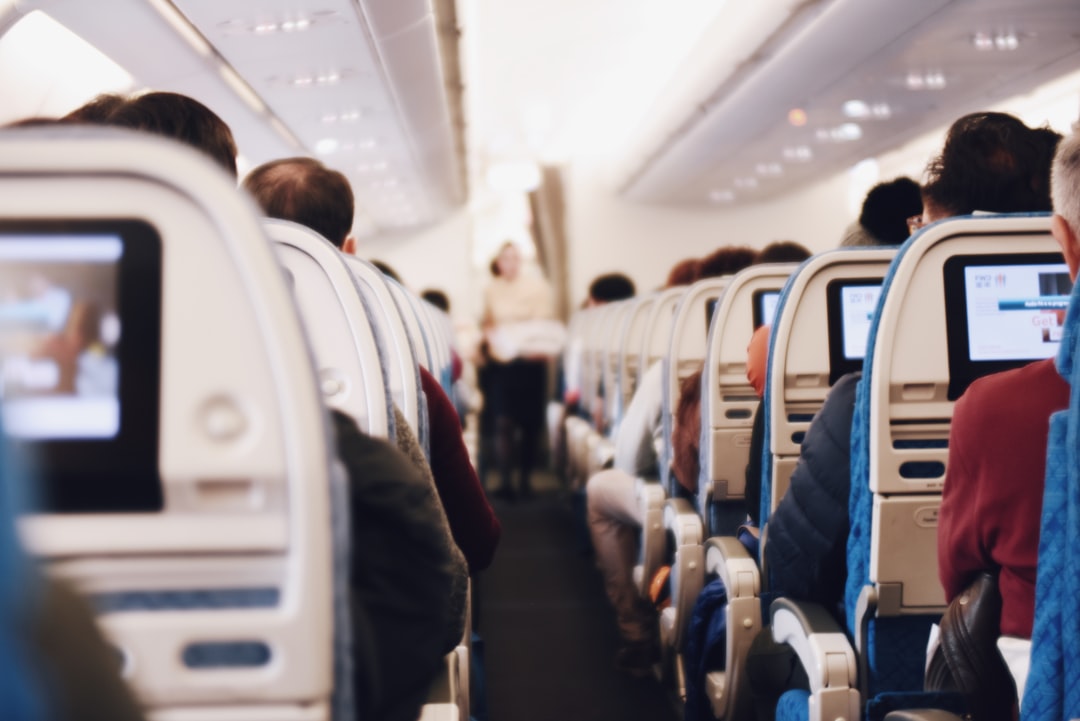 A view of the airplane aisle with a flight attendant carrying a tray