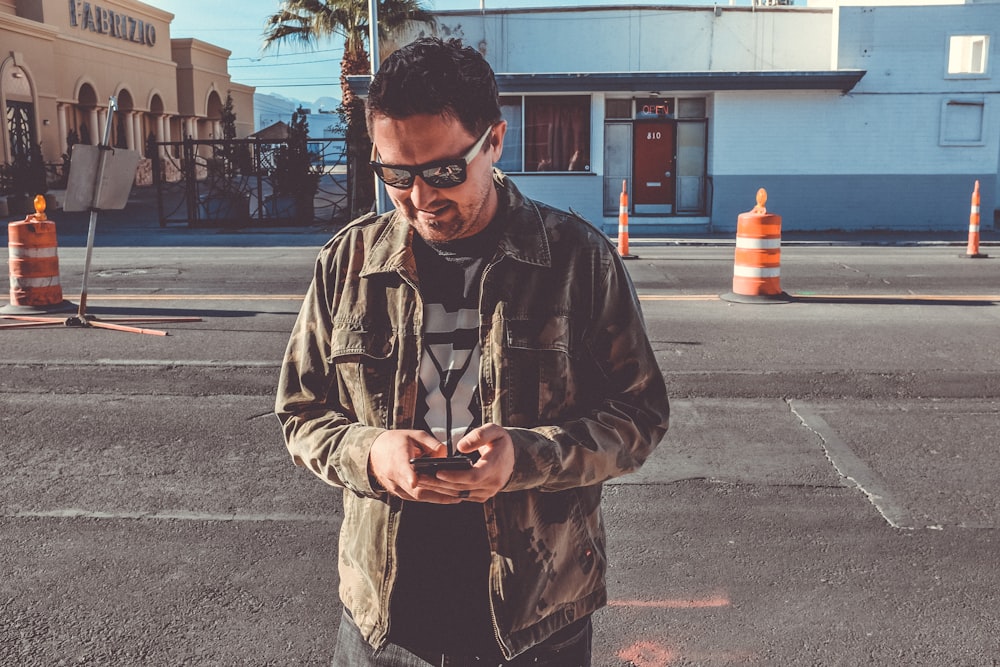 man holding smartphone near road