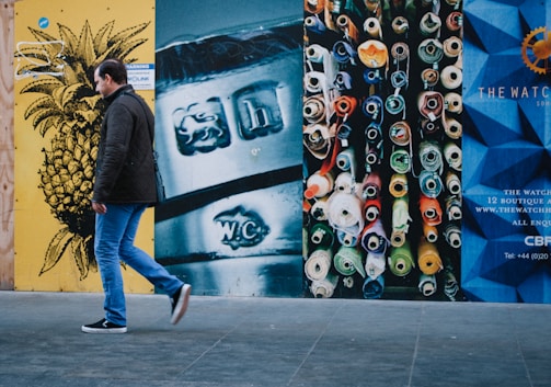 man walking near multicolored painted wall