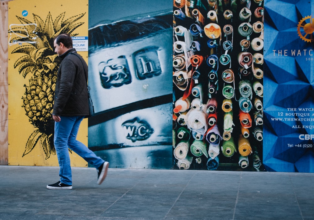 man walking near multicolored painted wall