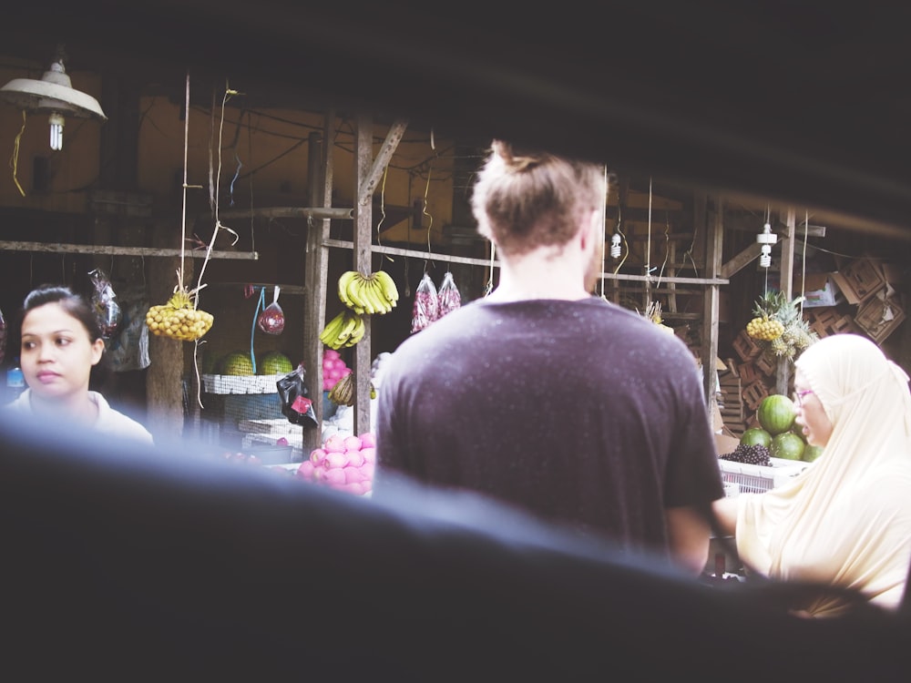 a man and a woman standing in front of a fruit stand