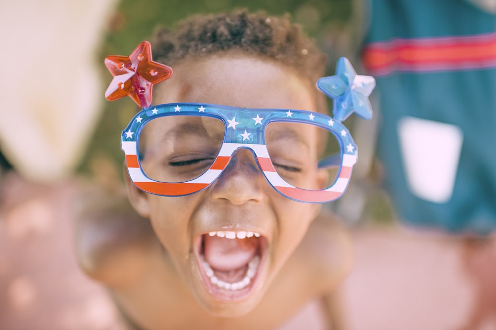 Junge mit amerikanischer Flaggenbrille, die seinen Mund offen hält