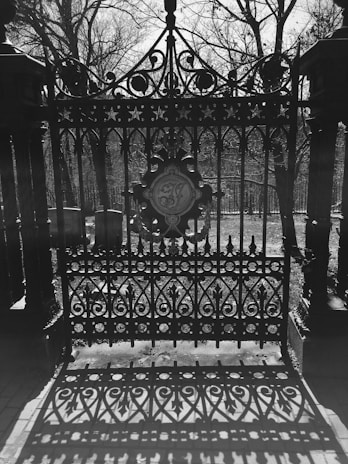 Ghostly wisps weaving through the wrought iron gates of a historic Memphis cemetery at night.
