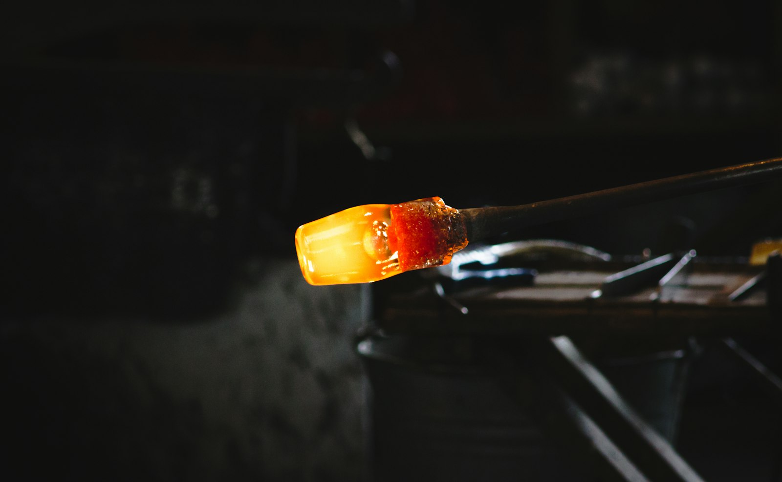Molten glass glowing on the end of a steel blowpipe