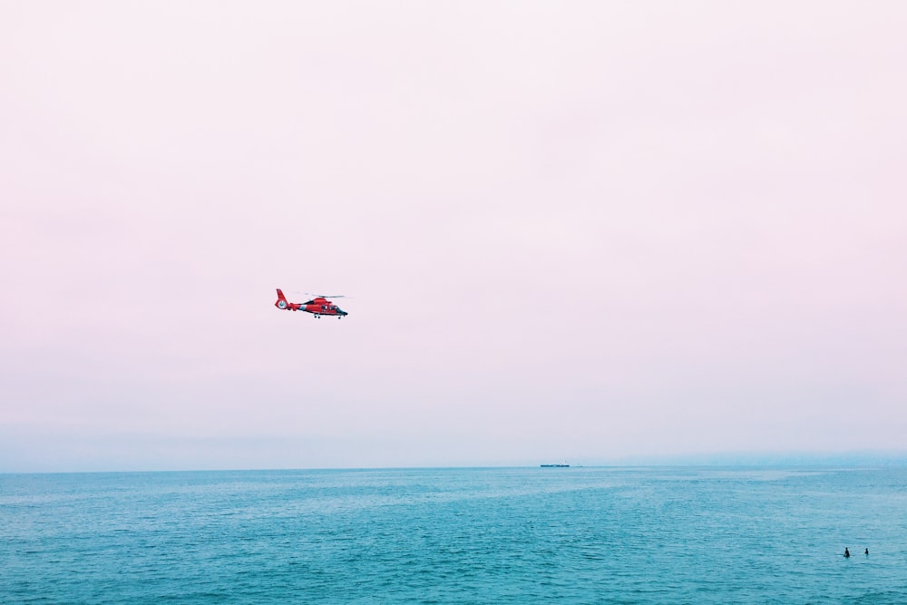 海上の空中に浮かぶ赤い飛行機