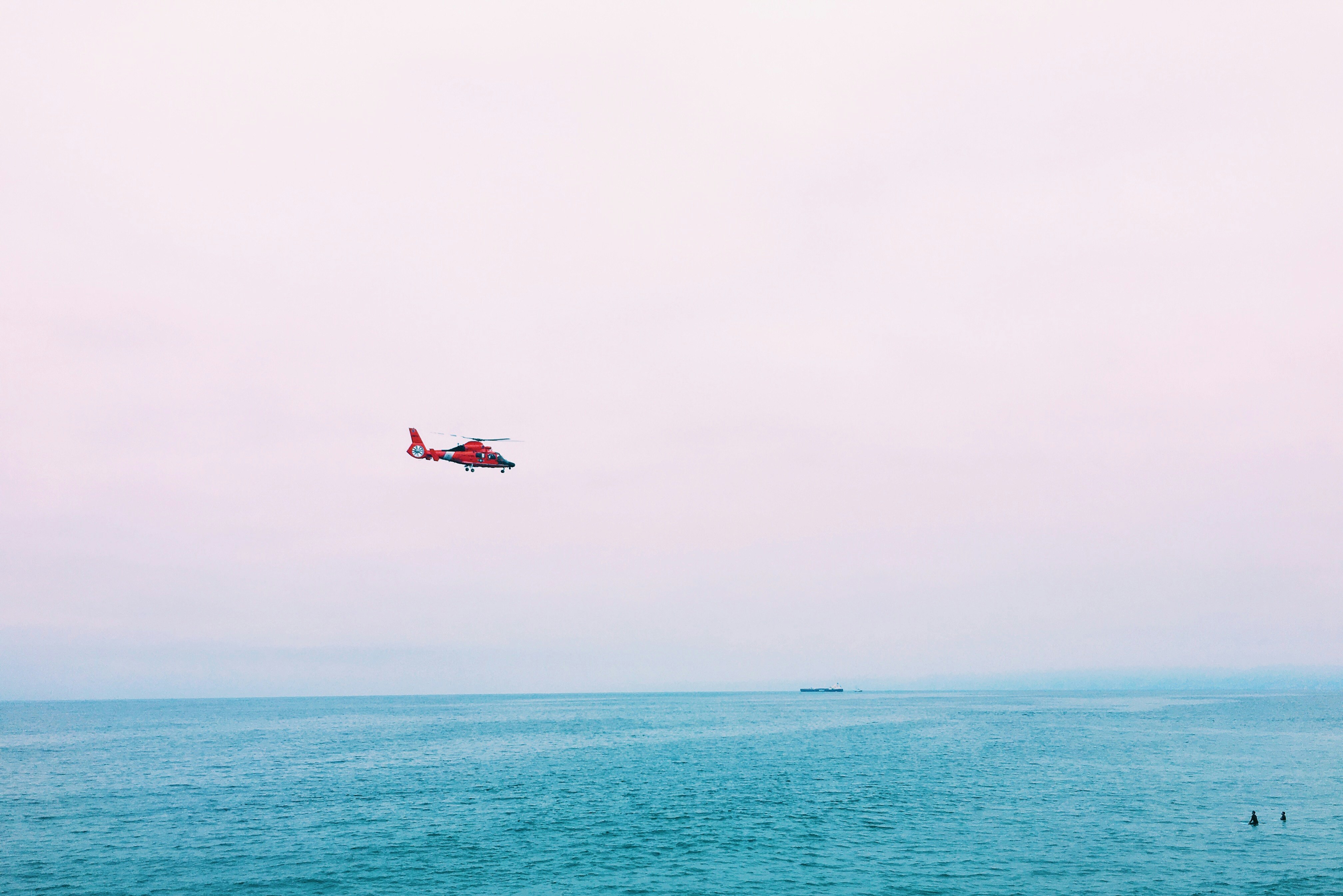 red plane on mid air above sea