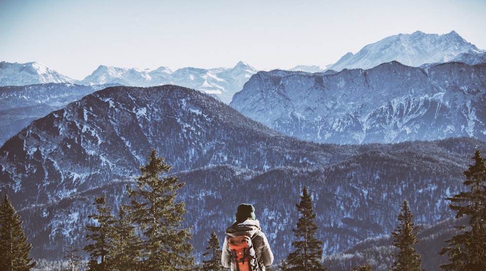 person wearing backpack near mountain during daytim