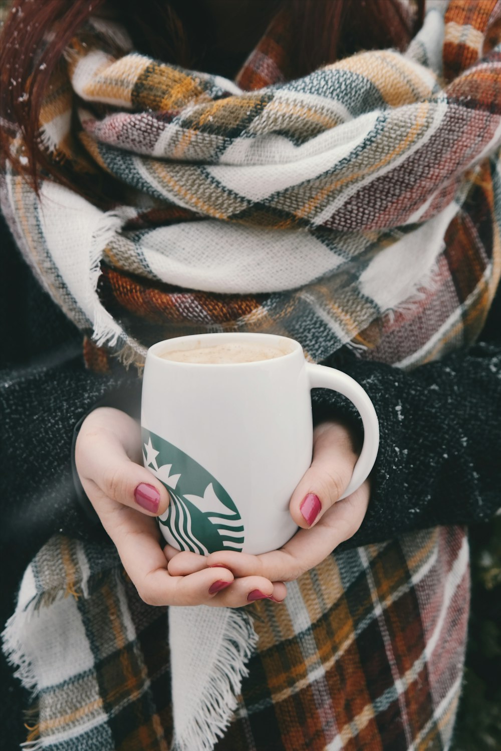 Person mit weißem und grünem Starbucks-Keramikbecher