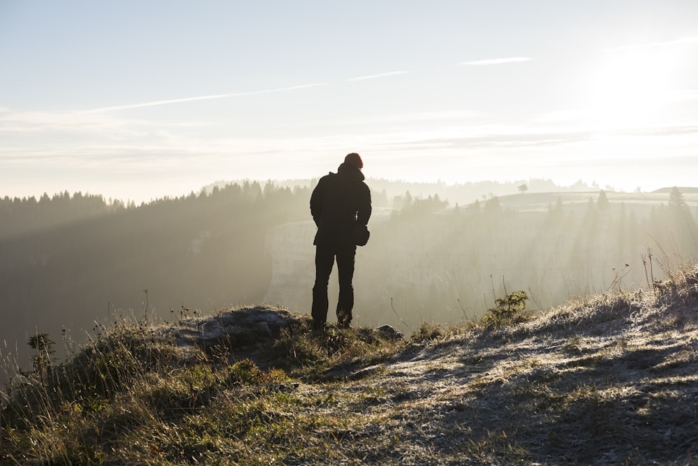 Mann, der tagsüber auf einer Klippe in der Nähe von Bäumen steht