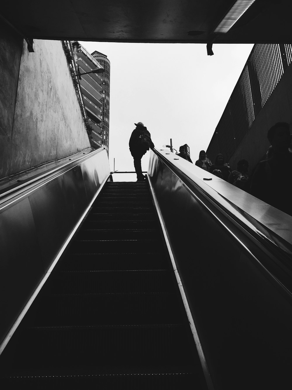 silhouette of person standing beside escalator during daytime